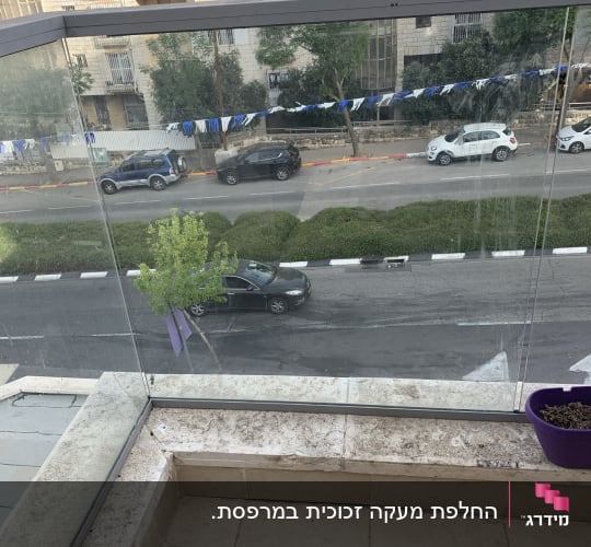 מעקה זכוכית שקוף במרפסת עם נוף לרחוב